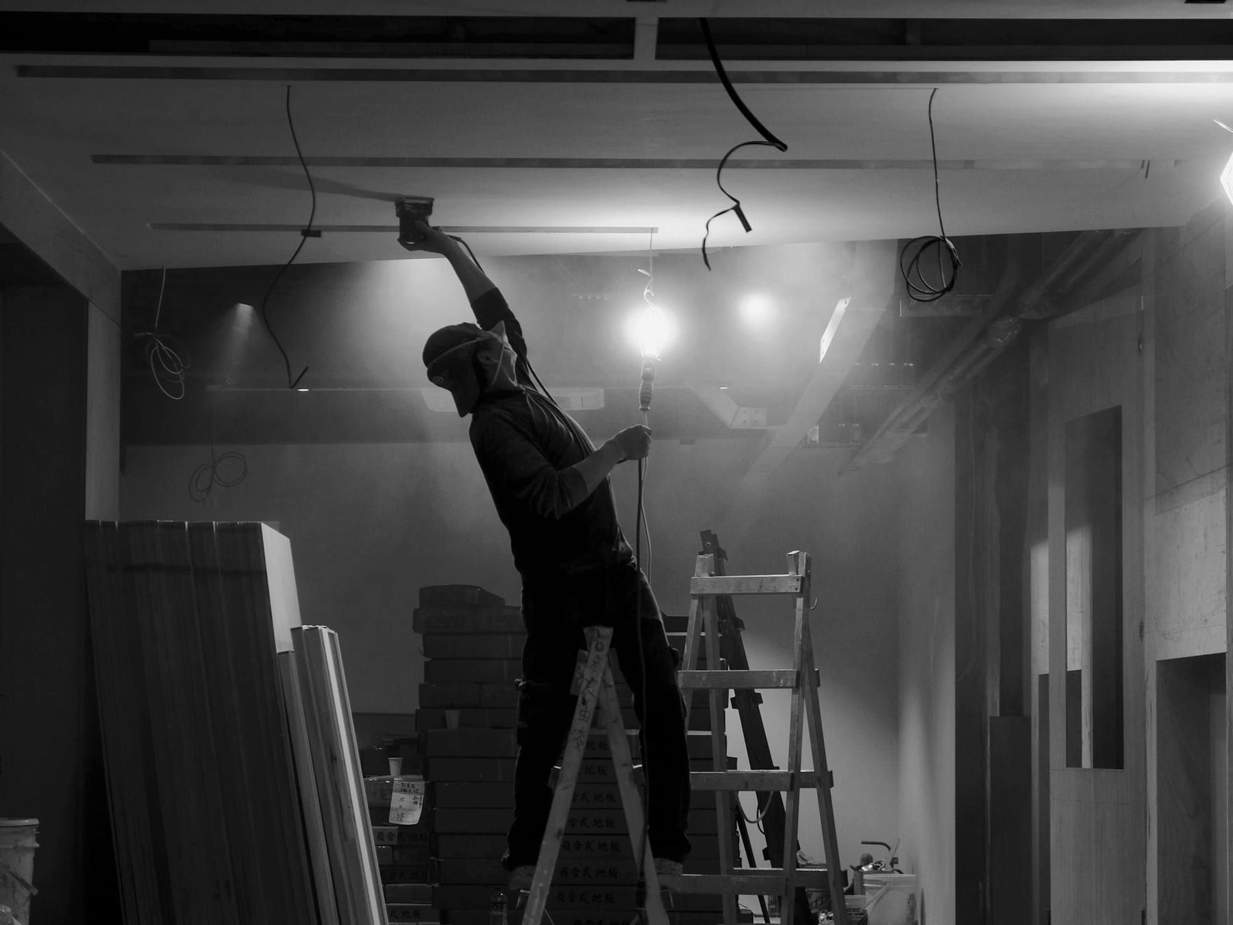 Worker on a stepladder finishing a ceiling during an interior renovation on site