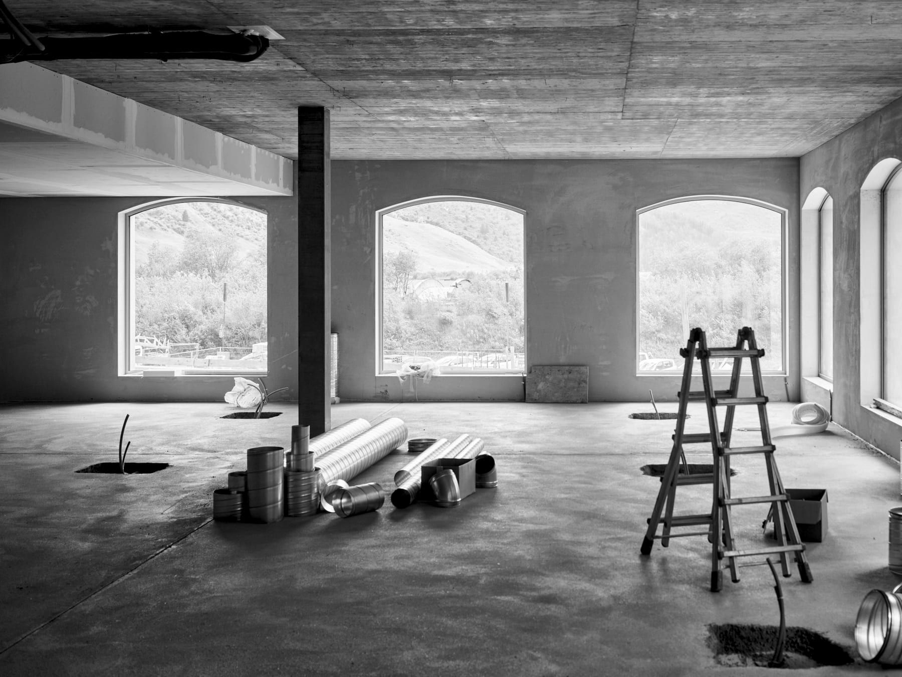 Stripped-out commercial interior during a fit-out, with exposed ductwork and a stepladder on site